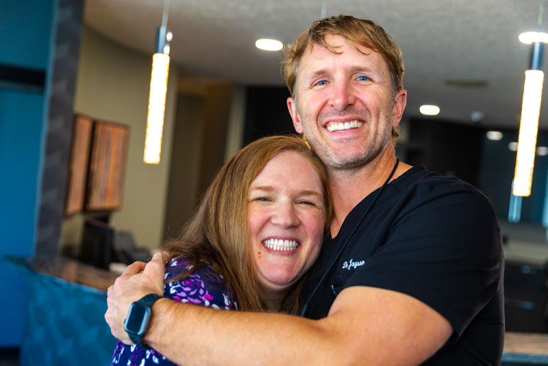 Crystal, A Dental Implant All On 4 Patient, Smiling And Being Hugged By Dr. Tabor