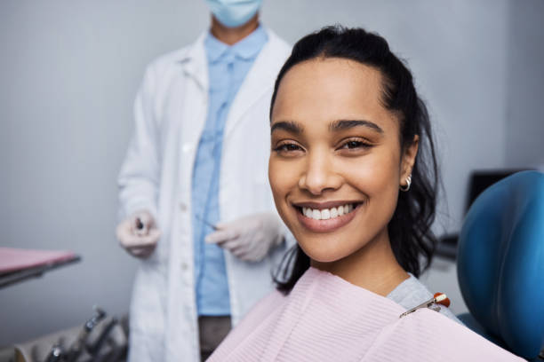 a woman smiling at the camera while the dentist is behind her