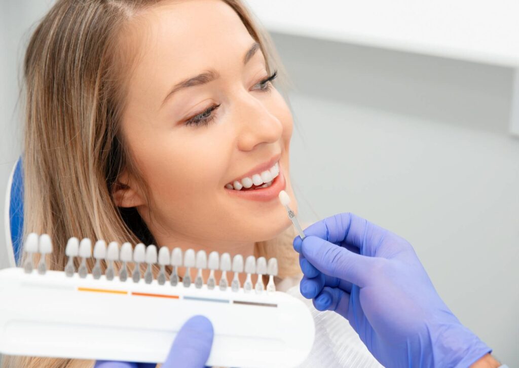 Dentist comparing veneer shade options with a patient during a cosmetic dentistry consultation about permanent veneers.