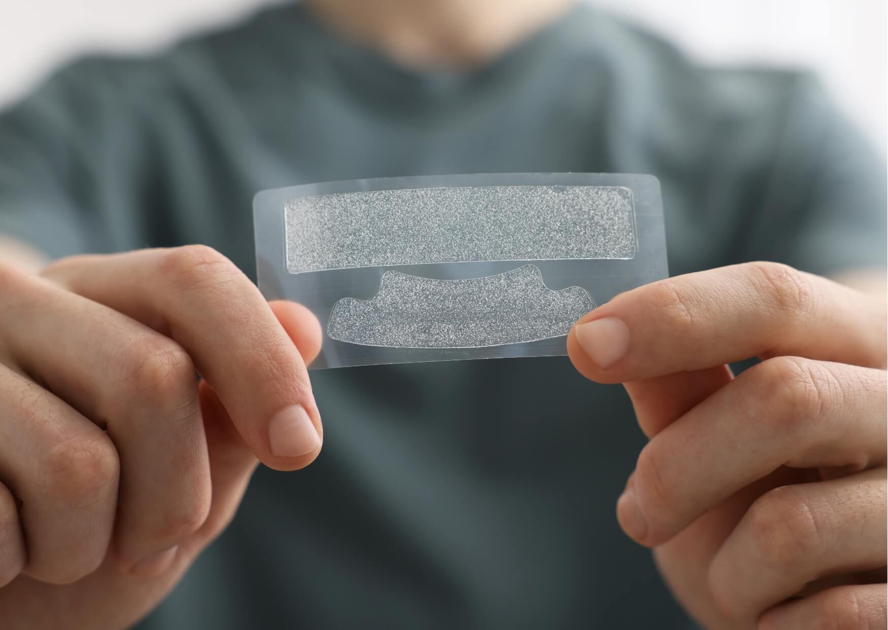Teeth whitening strips held in hand, showing an over-the-counter option for improving tooth color and reducing surface stains.