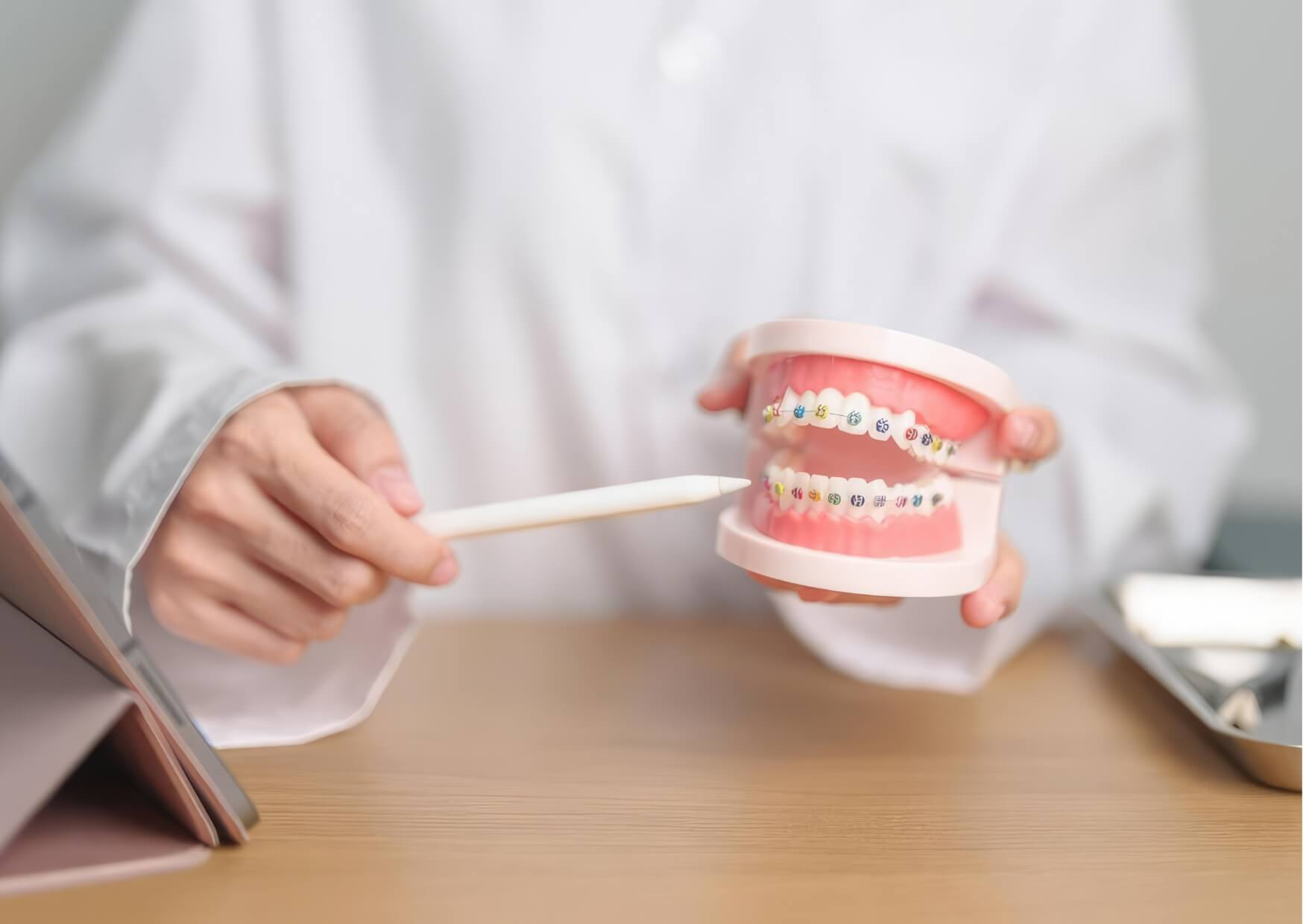 Orthodontist using a braces model to explain which candies to avoid while wearing braces to help prevent damage and tooth decay.