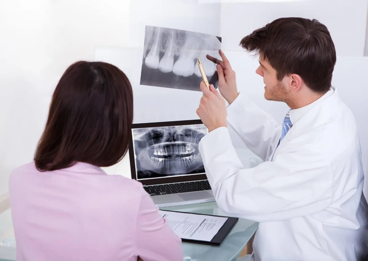 Dentist reviewing dental X-rays with a patient to assess the need for a bone graft before dental implants.