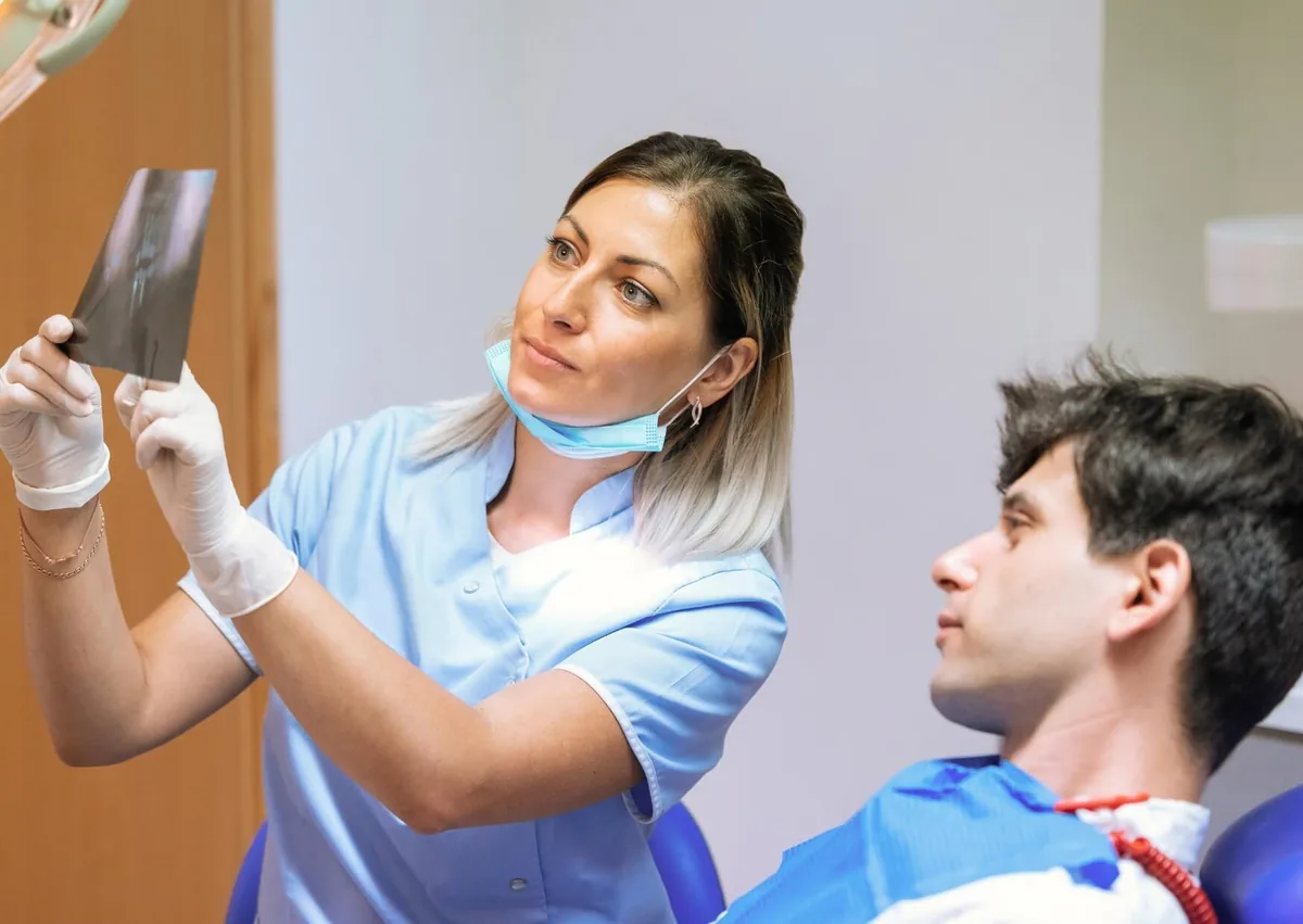 Dental professional reviewing an X-ray with a patient during an evaluation for zygomatic dental implants.